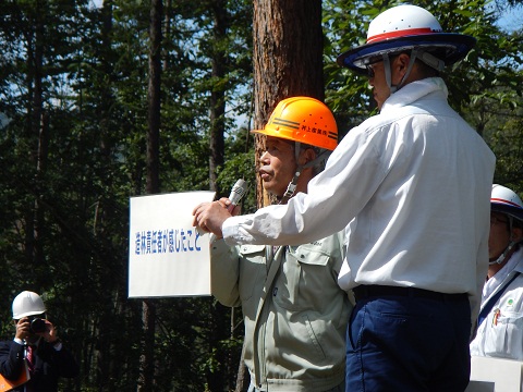 現場で苦労したポイントを話す現場代理人と、パネルを持って補助している森林技術指導官の写真