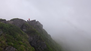 曇り模様の山頂付近に登山者がいる様子