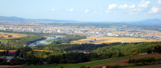 トトロ(戸外炉）峠より石狩川と高速道路が見え、その奥が深川市街地です。稲作は、刈り払い最盛期です。