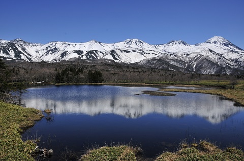 雪化粧した知床連山とその様子が水面に映っている写真