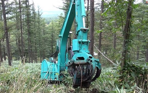 重機にアタッチメント（特注のレーキ）を付けて地拵（じごしらえ）作業を行っている写真