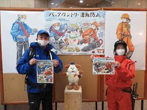 山岳遭難防止ポスターの前で取材を受ける