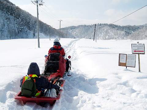 現場へは雪に閉ざされた林道を、まずはスノーモビルで走ります。