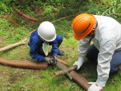 丸太切りする児童と見守る職員職員