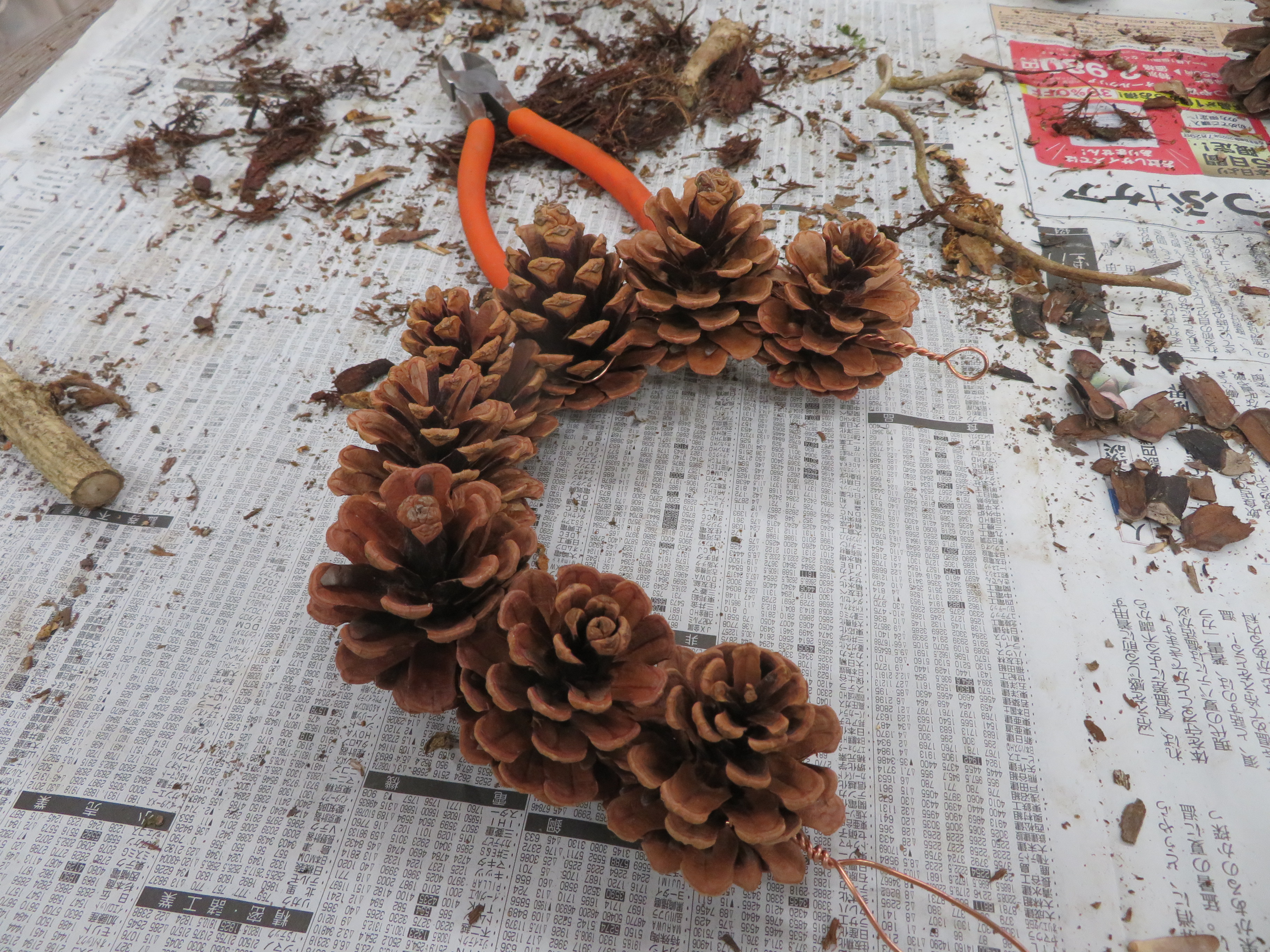 棒状になった松ぼっくりを曲げて輪の形にした様子