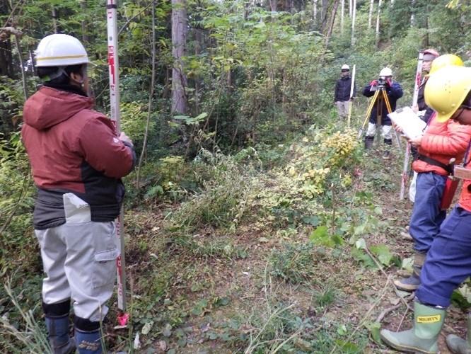 測量実周（レベルによる高さの計測を行っている様子）