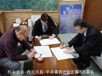 杉永会長・西元市長・平井署長の協定書への署名の様子