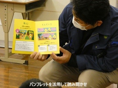 パンフレットを児童の目線で見せながら読み聞かせする様子