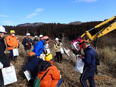 下刈実演の重機を確認する参加者