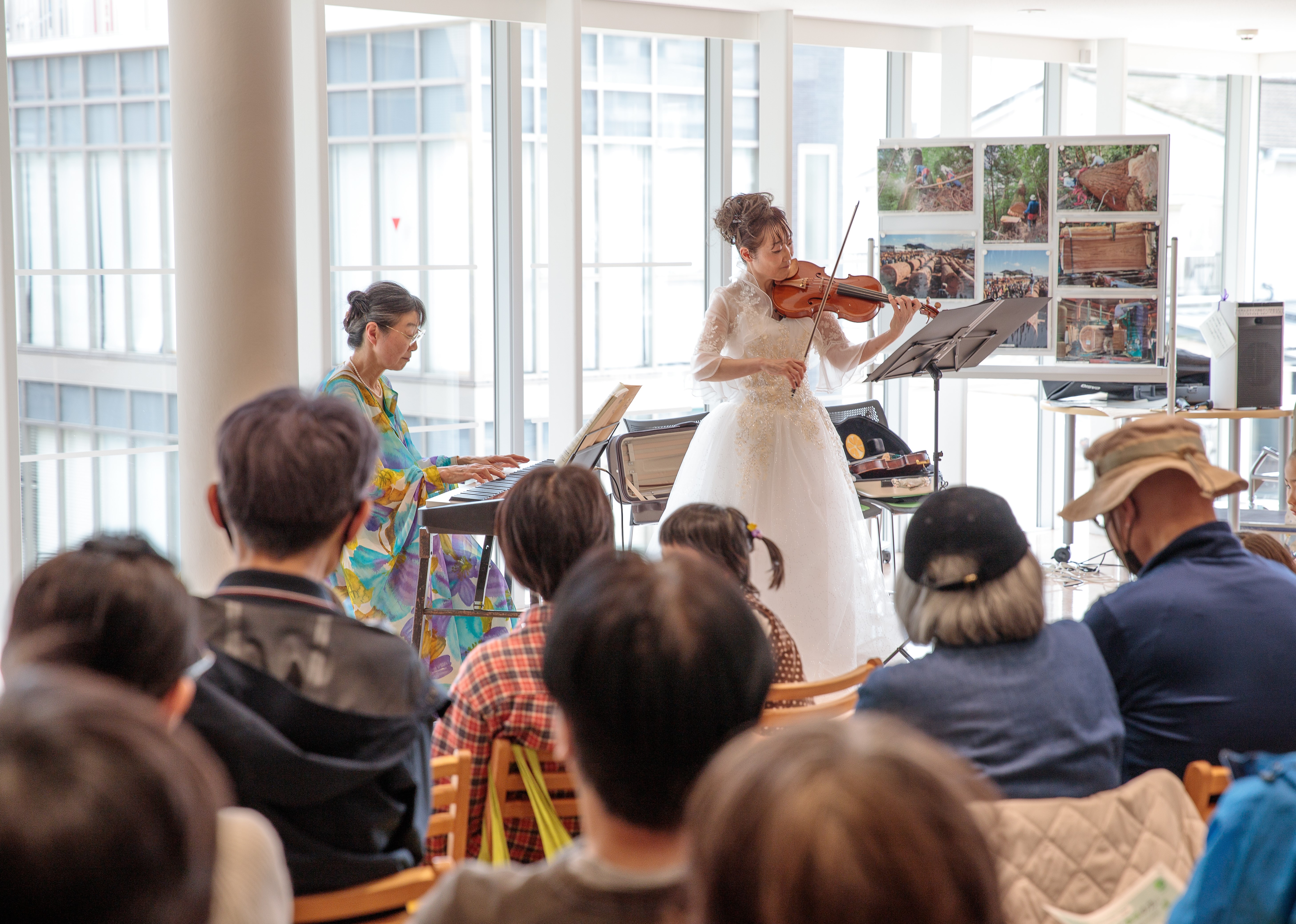 「森の音楽会」の様子。奥にヴァイオリンとピアノの演奏者がそれぞれの楽器を演奏している。手前には観客の後ろ姿が写っている。